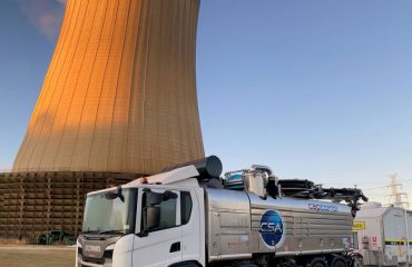 vacuum truck positioned in front of a large industrial cooling tower